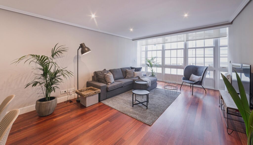 Salón luminoso con sofá, sillón y ventanales en apartamento de alquiler en A Coruña