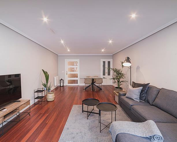 Salón amplio con sofá, comedor y decoración minimalista en apartamento de alquiler en A Coruña